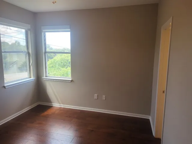 an empty room with wooden floor and windows