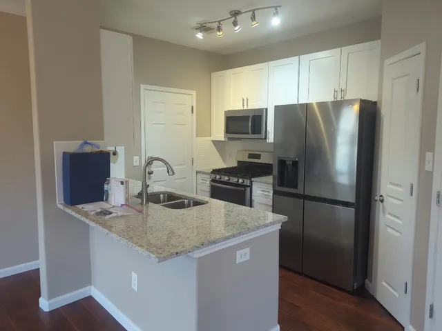 a kitchen with stainless steel appliances granite countertop a refrigerator a stove a sink and a microwave