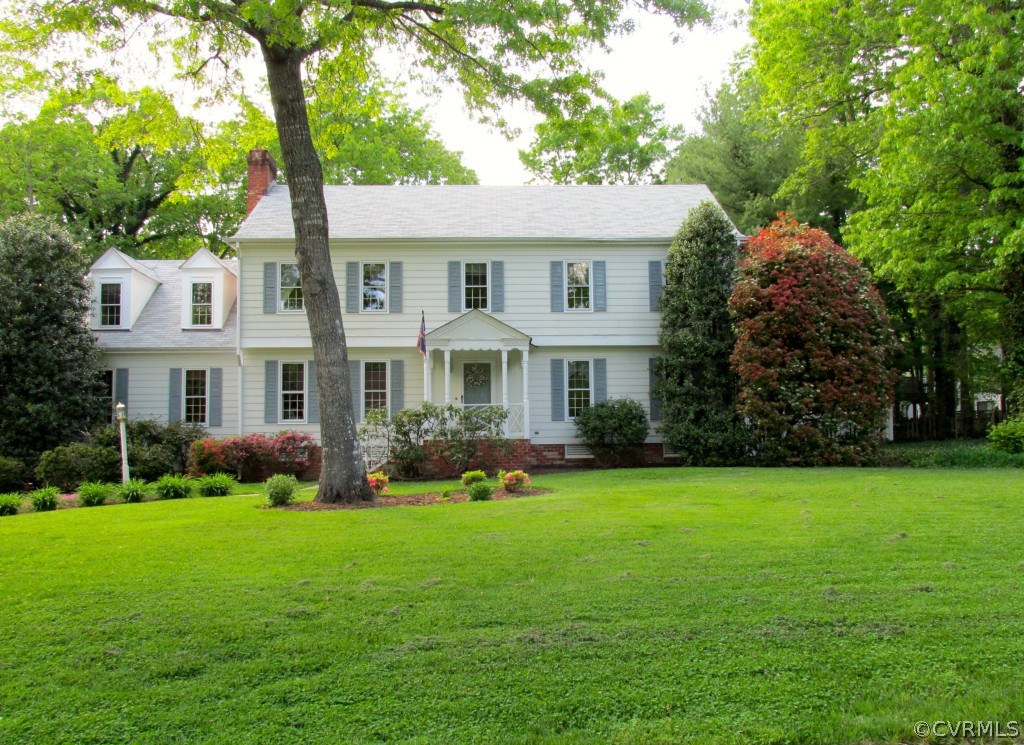 a front view of a house with garden and trees