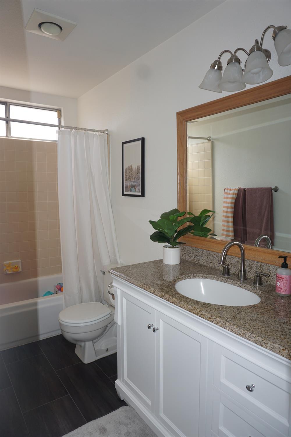 954 Wake Forest Court Merced, CA 95348 - Photo 20 of 36 a bathroom with a granite countertop toilet a sink and a mirror