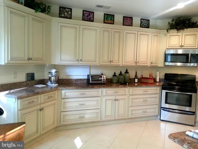 a kitchen with stainless steel appliances granite countertop a stove a sink and a white cabinets