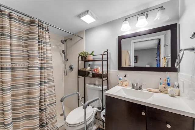a bathroom with a granite countertop sink vanity mirror and toilet