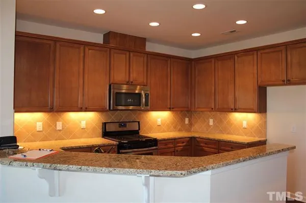a kitchen with kitchen island granite countertop a sink a stove cabinets and a counter top space