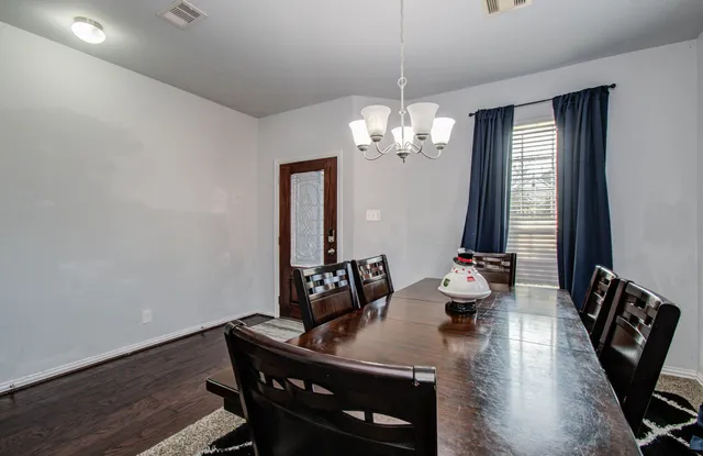 a view of a dining room with furniture a chandelier and wooden floor
