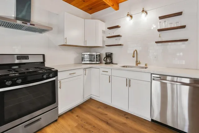 a kitchen with cabinets stainless steel appliances and wooden floor