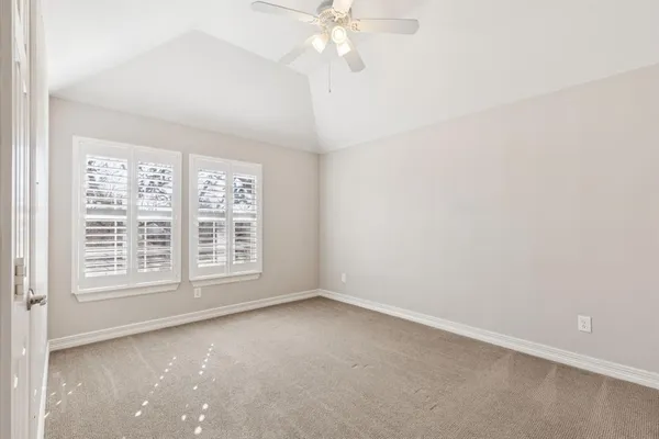 an empty room with a chandelier fan and windows
