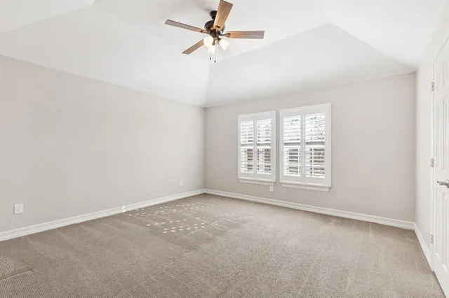 an empty room with a chandelier fan and windows