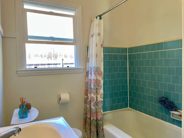 a bathroom with a sink a toilet a window and a shower