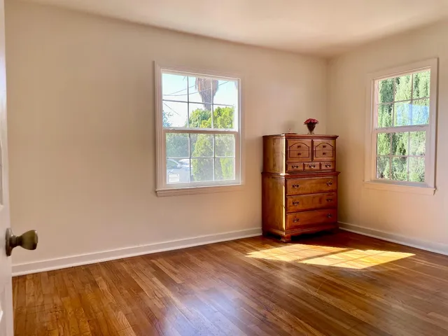 a view of an empty room with wooden floor and closet area