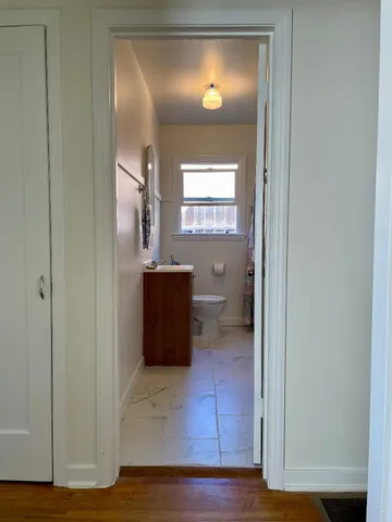 a view of a hallway with wooden floor windows and a bathroom