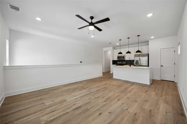 a kitchen with stainless steel appliances kitchen island granite countertop a sink a stove and a wooden floors