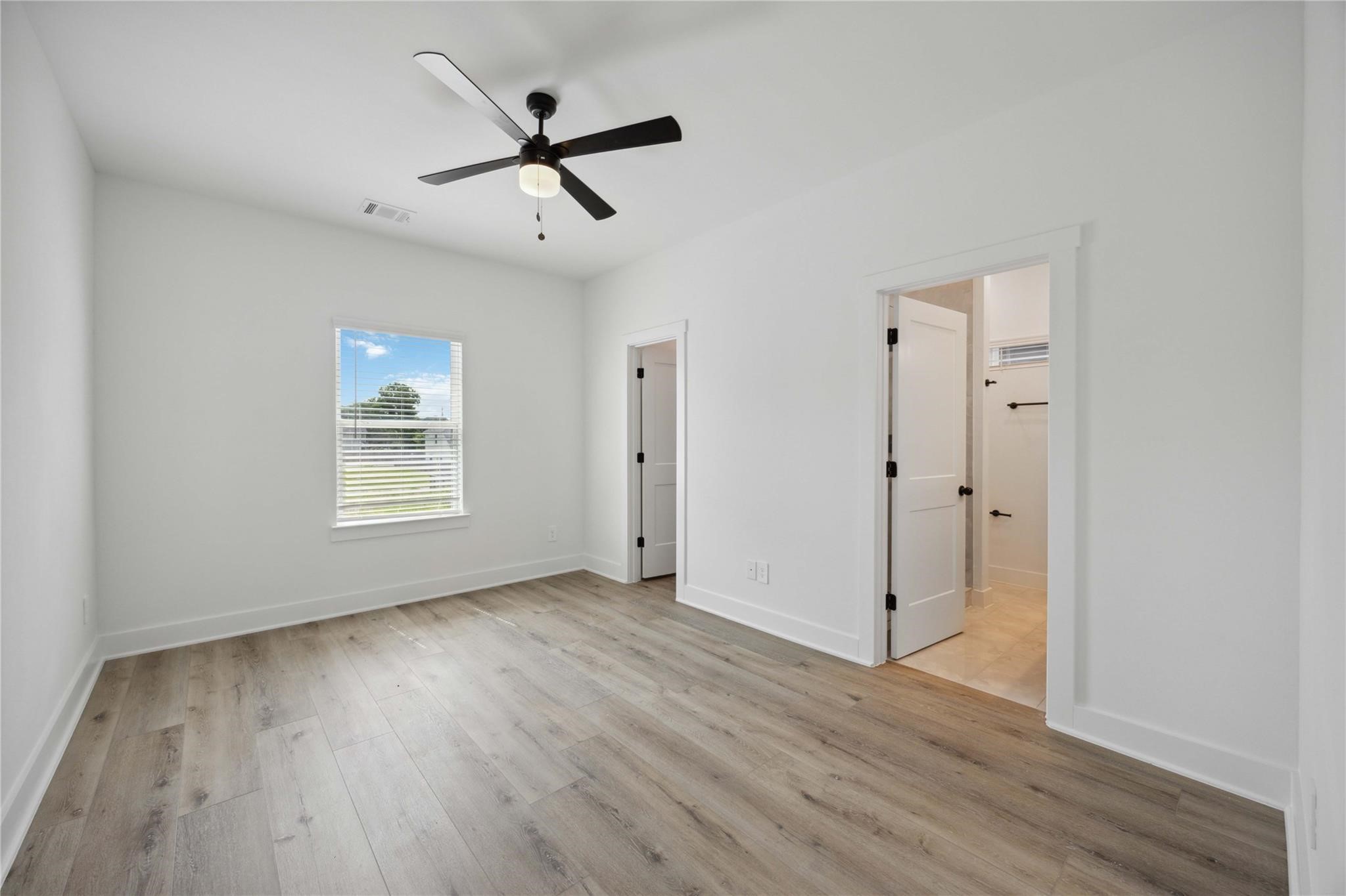 8017 A Cora Street Houston, TX 77088 - Photo 25 of 29 an empty room with wooden floor a ceiling fan and windows