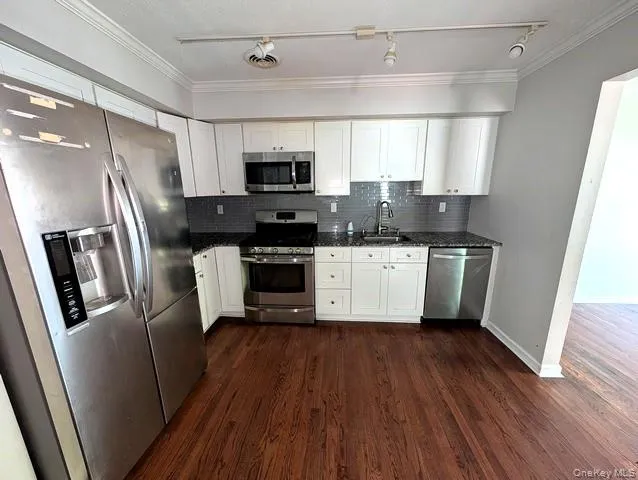 a kitchen with stainless steel appliances a refrigerator a sink a stove a microwave and wooden floors
