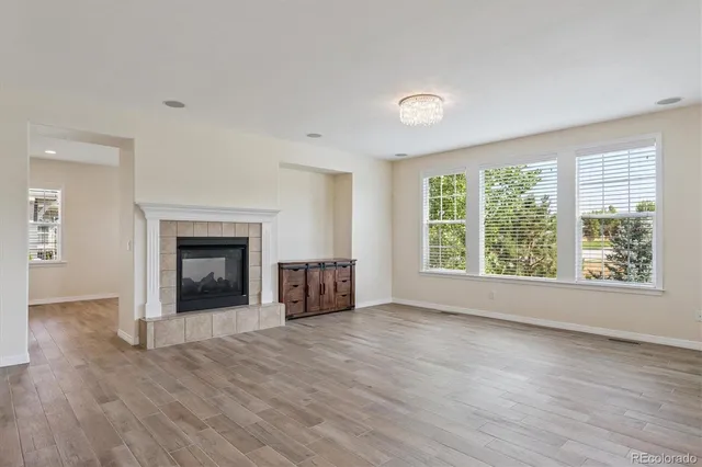 an empty room with windows a fireplace and wooden floor