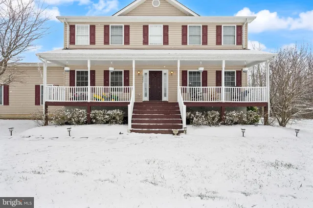 a front view of a house with a yard covered in snow