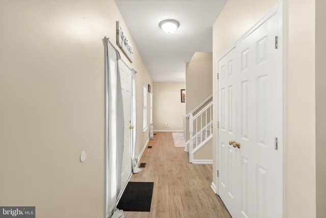 a view of a hallway to a livingroom with wooden floor and staircase