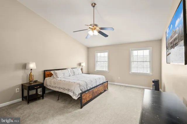a bedroom with a bed ceiling fan and a wooden floor