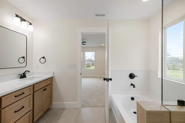 a bathroom with a tub sink double vanity and mirror