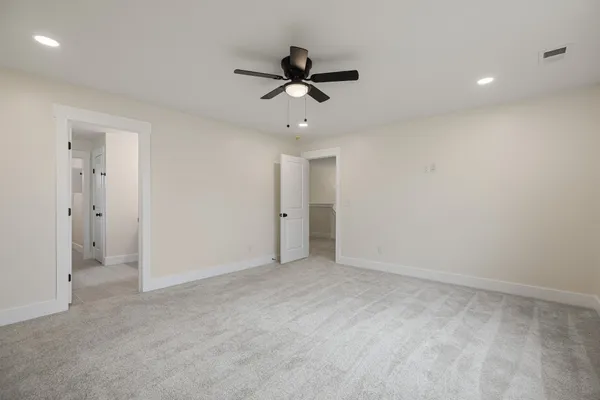 a view of an empty room and chandelier fan