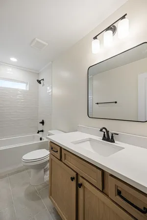a bathroom with a sink a toilet a mirror and shower