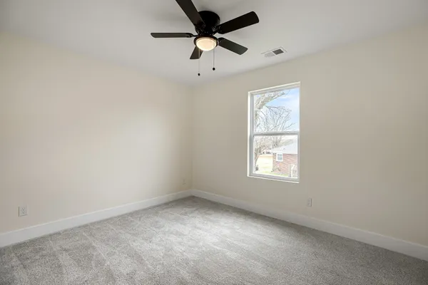an empty room with a window and a fan