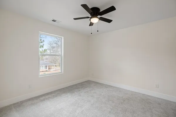 an empty room with a window and a fan