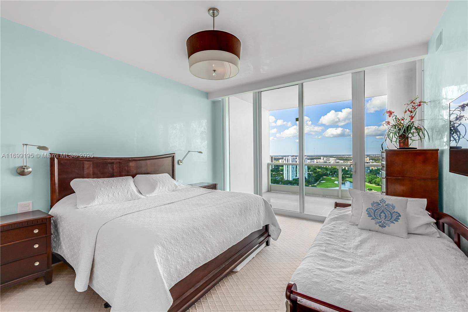 20155 Northeast 38th Court, Unit 2903 Aventura, FL 33180 - Photo 19 of 28 a bedroom with a bed a chandelier and large window