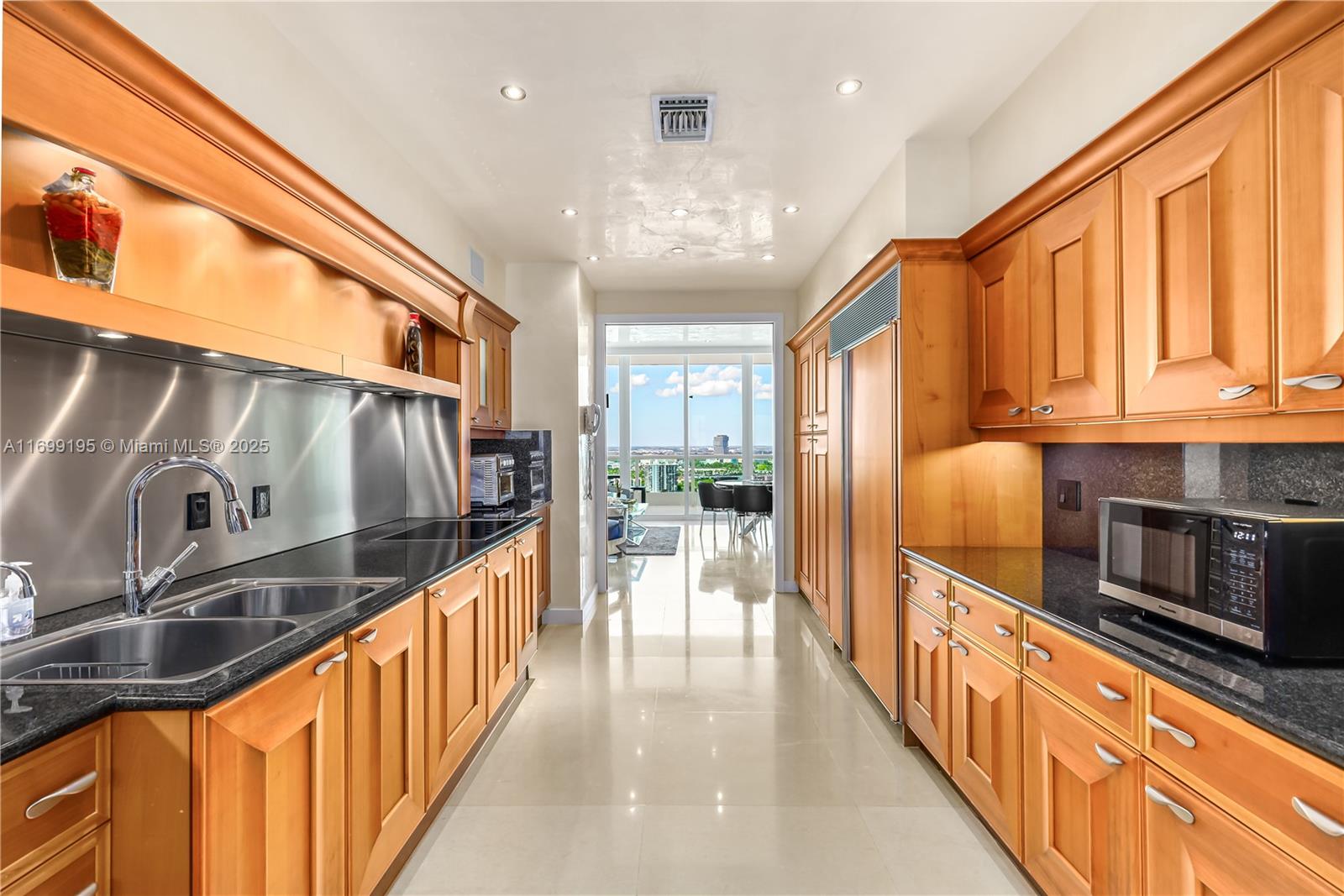 20155 Northeast 38th Court, Unit 2903 Aventura, FL 33180 - Photo 3 of 28 a kitchen with stainless steel appliances granite countertop a refrigerator a stove and a sink with wooden floor