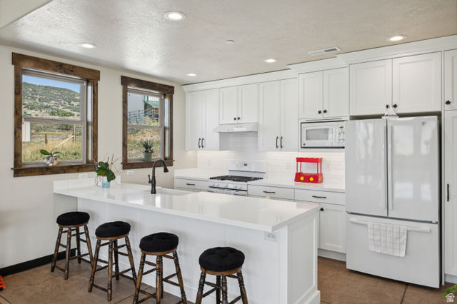 6117 North Rocky Ridge Road Peoa, UT 84061 - Photo 19 of 82 Bright kitchen featuring white cabinetry and a central island with a sink