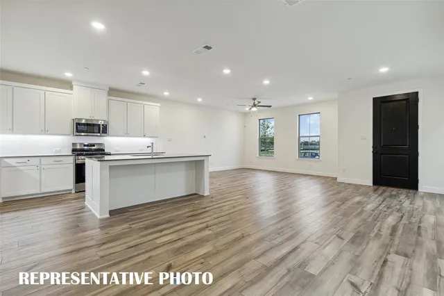 a view of kitchen with stainless steel appliances granite countertop a stove top oven a sink and a refrigerator