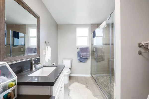 a bathroom with a granite countertop sink a mirror and a shower