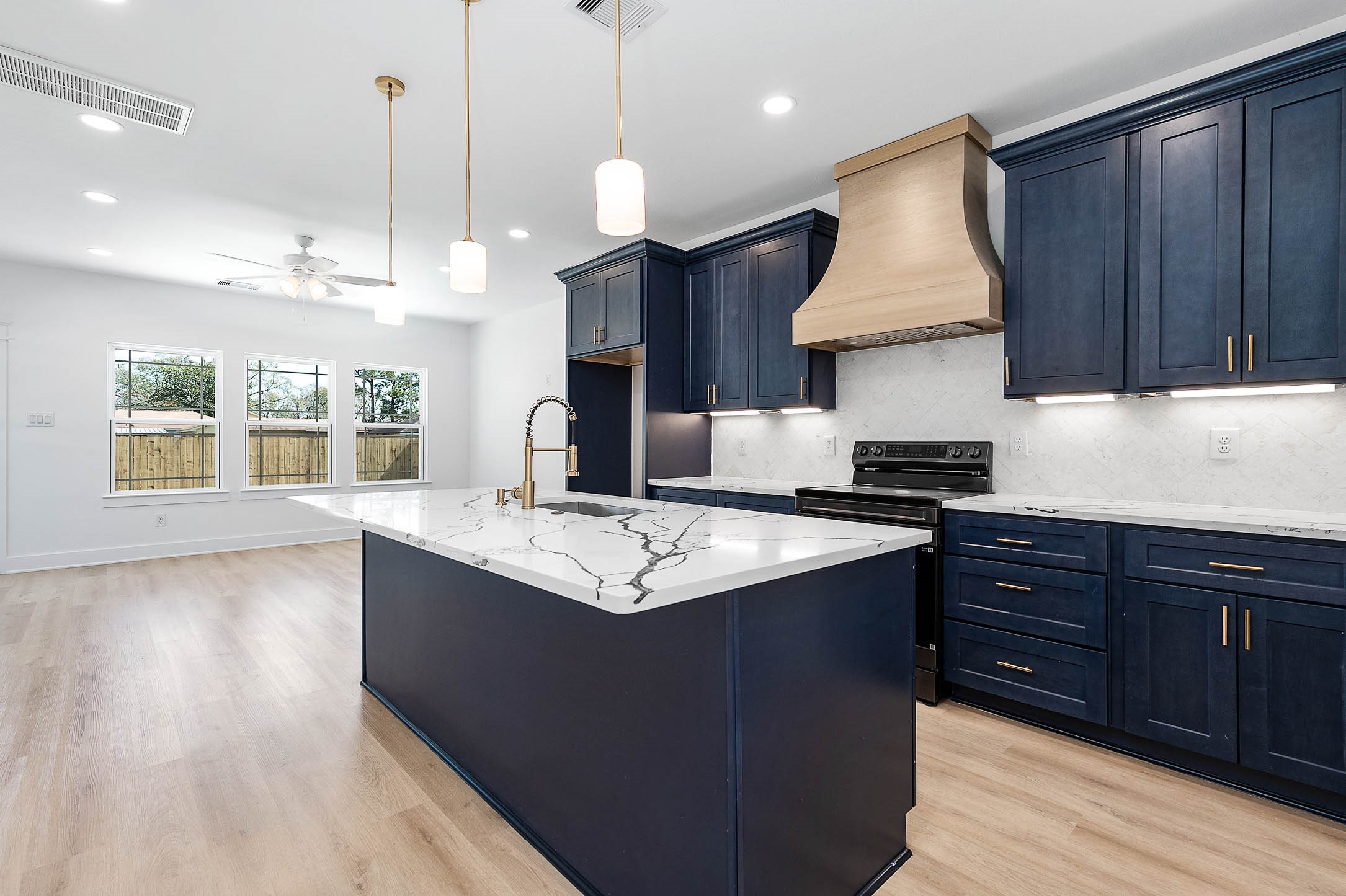8602 Hoffman Street Houston, TX 77016 - Photo 1 of 30 Open-concept kitchen featuring a large island, quartz countertops, and ash blue cabinetry.