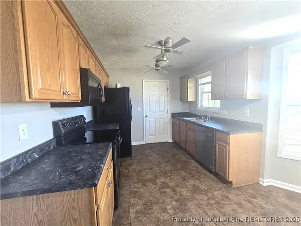 a kitchen with stainless steel appliances granite countertop a refrigerator a stove a sink and dishwasher with wooden floor