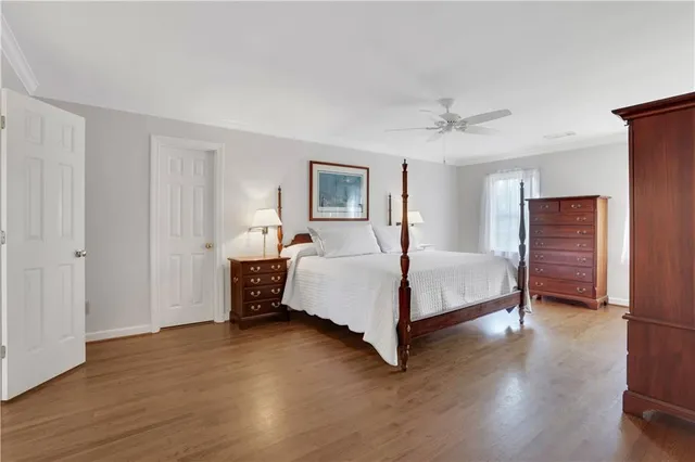 a bedroom with a bed table and two window