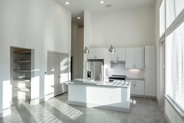 a large kitchen with kitchen island white cabinets and stainless steel appliances