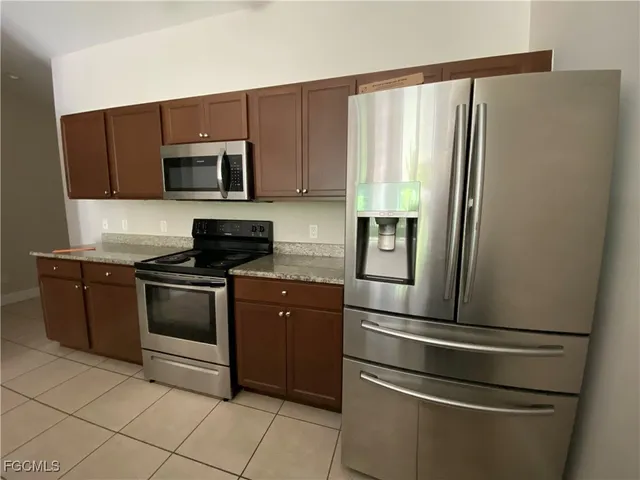 a kitchen with granite countertop a refrigerator stove and microwave