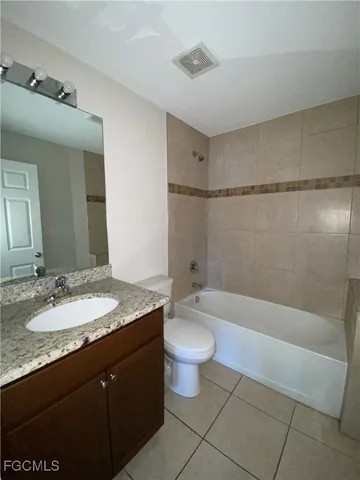 a bathroom with a granite countertop sink a toilet a mirror and bathtub