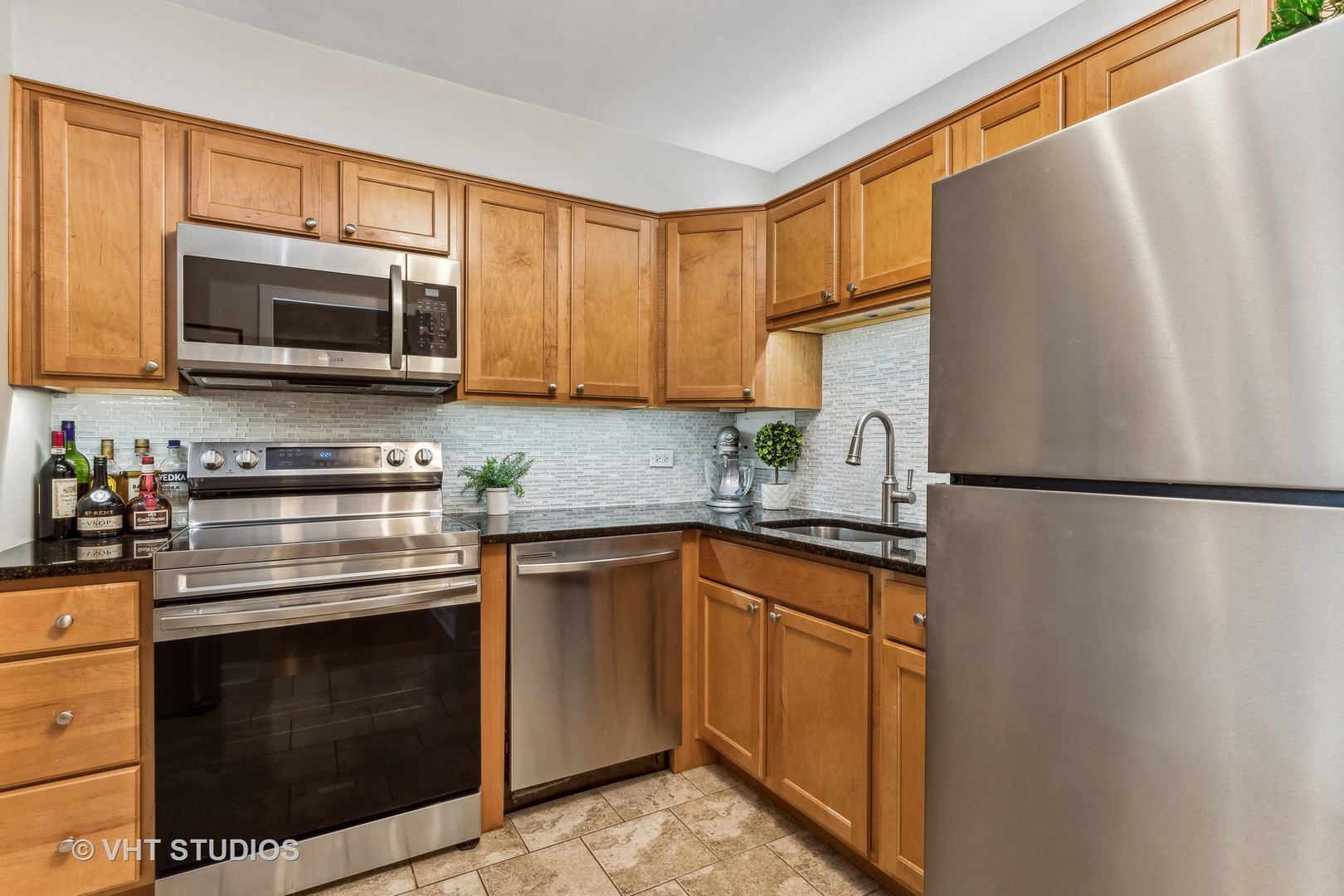 555 West Cornelia Avenue, Unit 412 Chicago, IL 60657 - Photo 5 of 20 a kitchen with stainless steel appliances granite countertop a refrigerator stove a sink dishwasher and microwave oven with cabinets