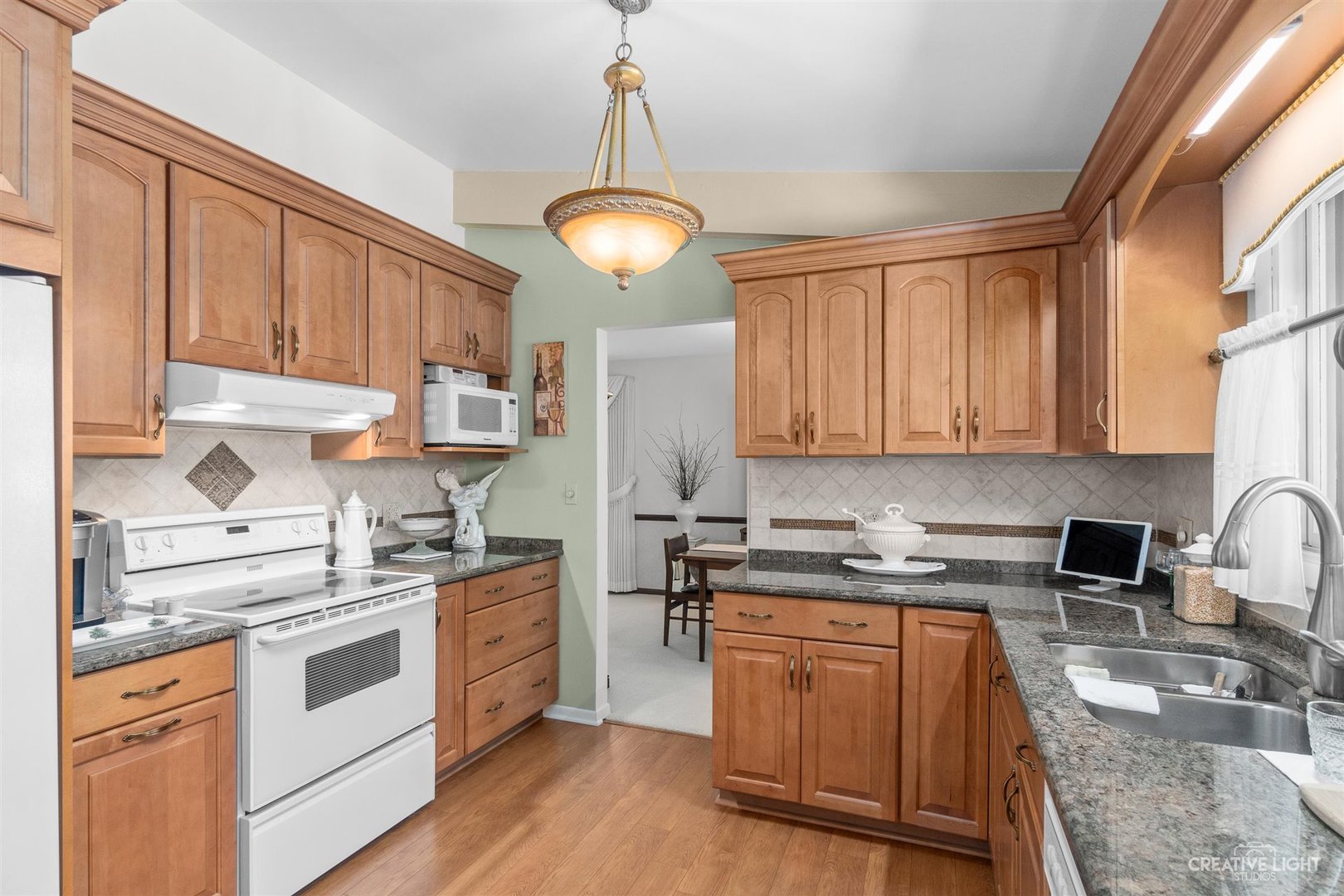 527 Sheffield Road Naperville, IL 60565 - Photo 8 of 27 a kitchen with stainless steel appliances granite countertop a stove a sink dishwasher and white cabinets with wooden floor