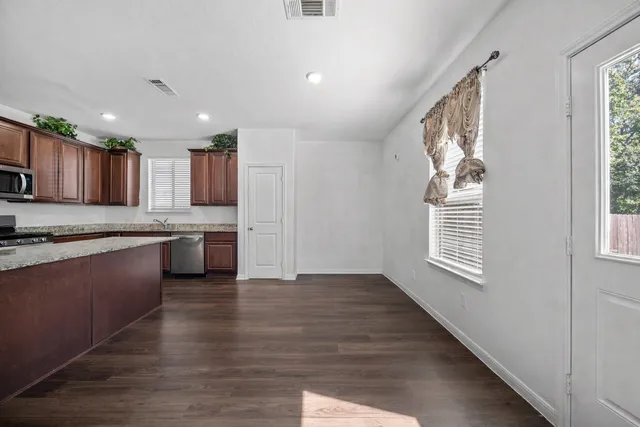 a kitchen with granite countertop wooden floors a sink stainless steel appliances and cabinets