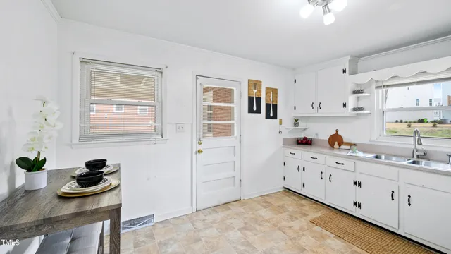 a kitchen with white cabinets and window