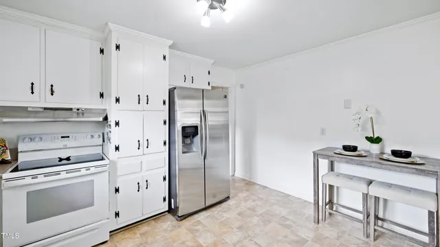 a kitchen with stainless steel appliances a stove a refrigerator and white cabinets