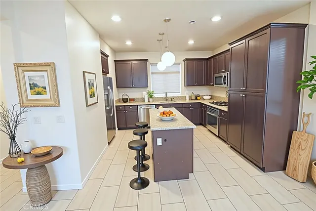 a kitchen with stainless steel appliances granite countertop a refrigerator a sink a stove top oven and a dining table with wooden floor