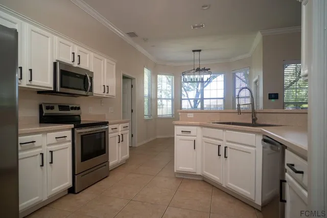 a kitchen with granite countertop white cabinets stainless steel appliances and a window