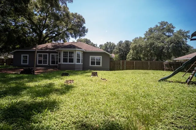 a view of a house with backyard and a tree