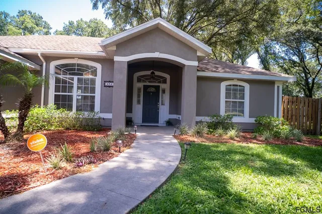 a front view of a house with a yard and potted plants