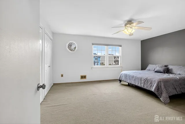 a spacious bedroom with a bed and a chandelier fan