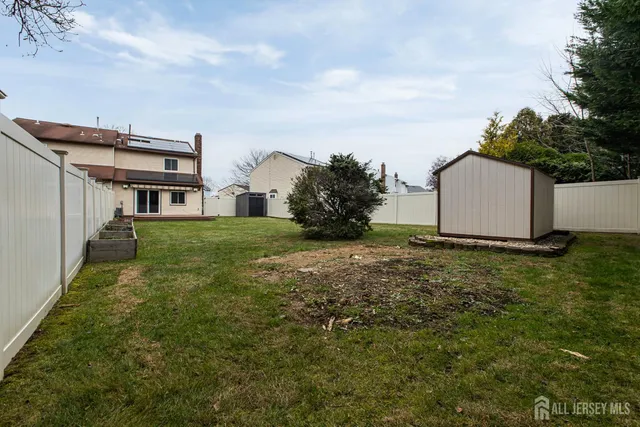 a view of a grey house with a big yard and large trees