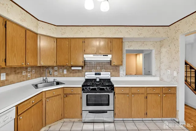 a kitchen with granite countertop a stove a sink and white cabinets