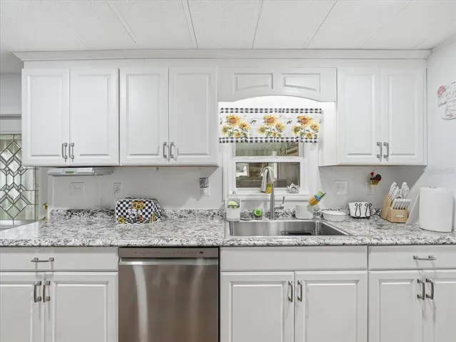 a kitchen with granite countertop white cabinets and a window
